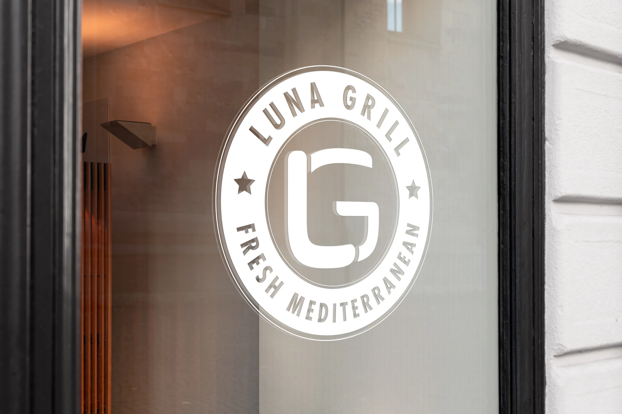 The monogram badge applied as frosted vinyl on a restaurant window