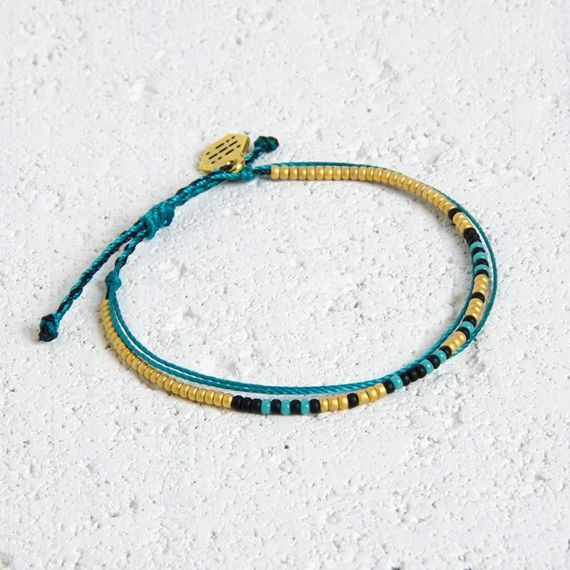 A close-up of the gold-plated Locality charm fastened to a finished bracelet.