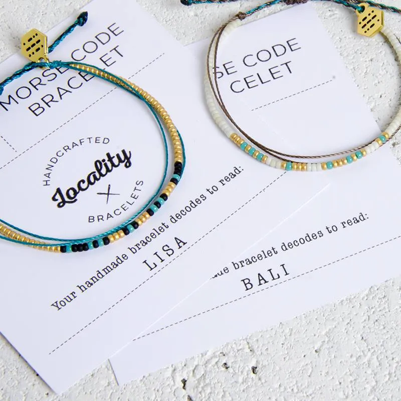 Two custom Locality bracelets laid side by side, spelling LISA and BALI in morse code beads.