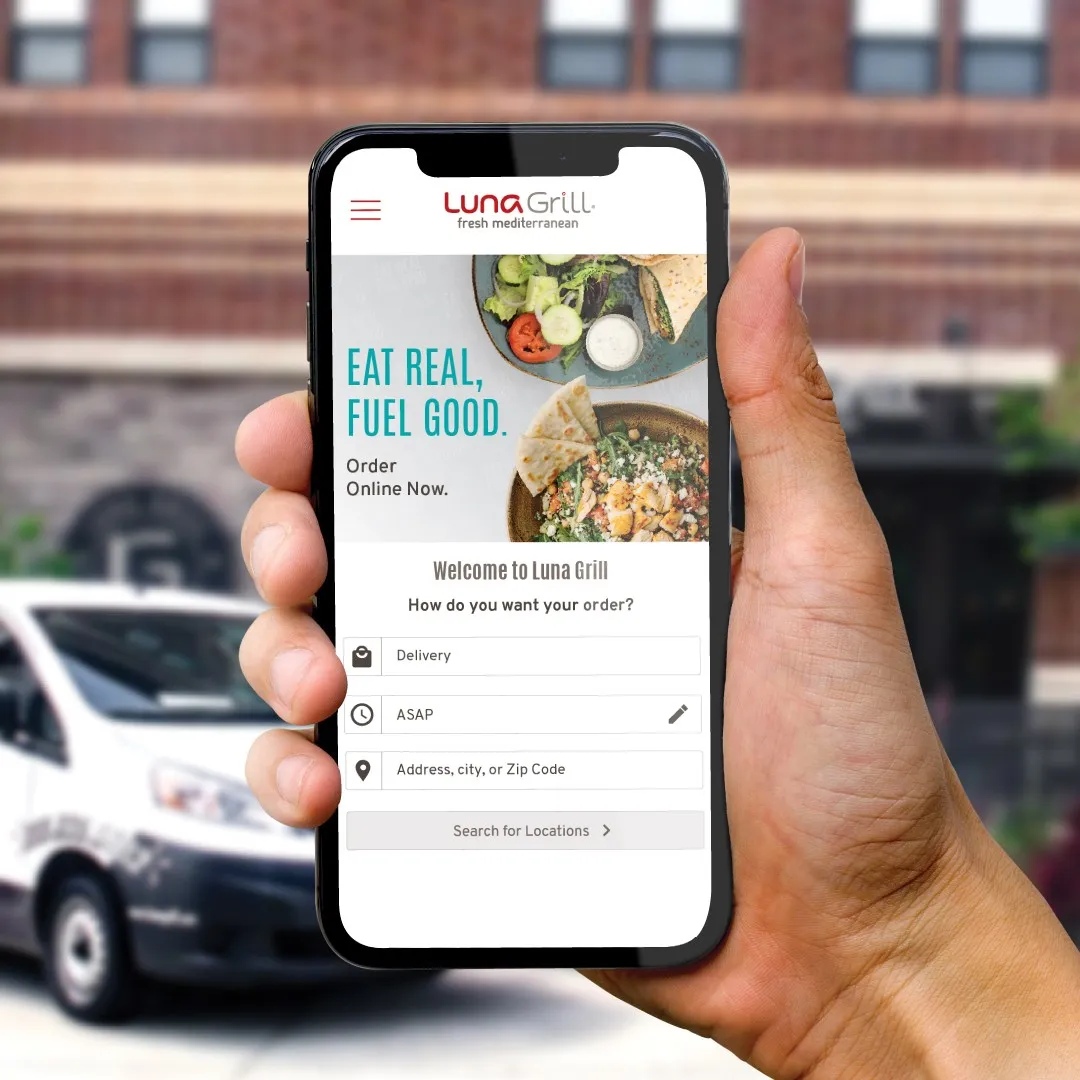 The Luna Grill ordering app open on a phone held in one hand