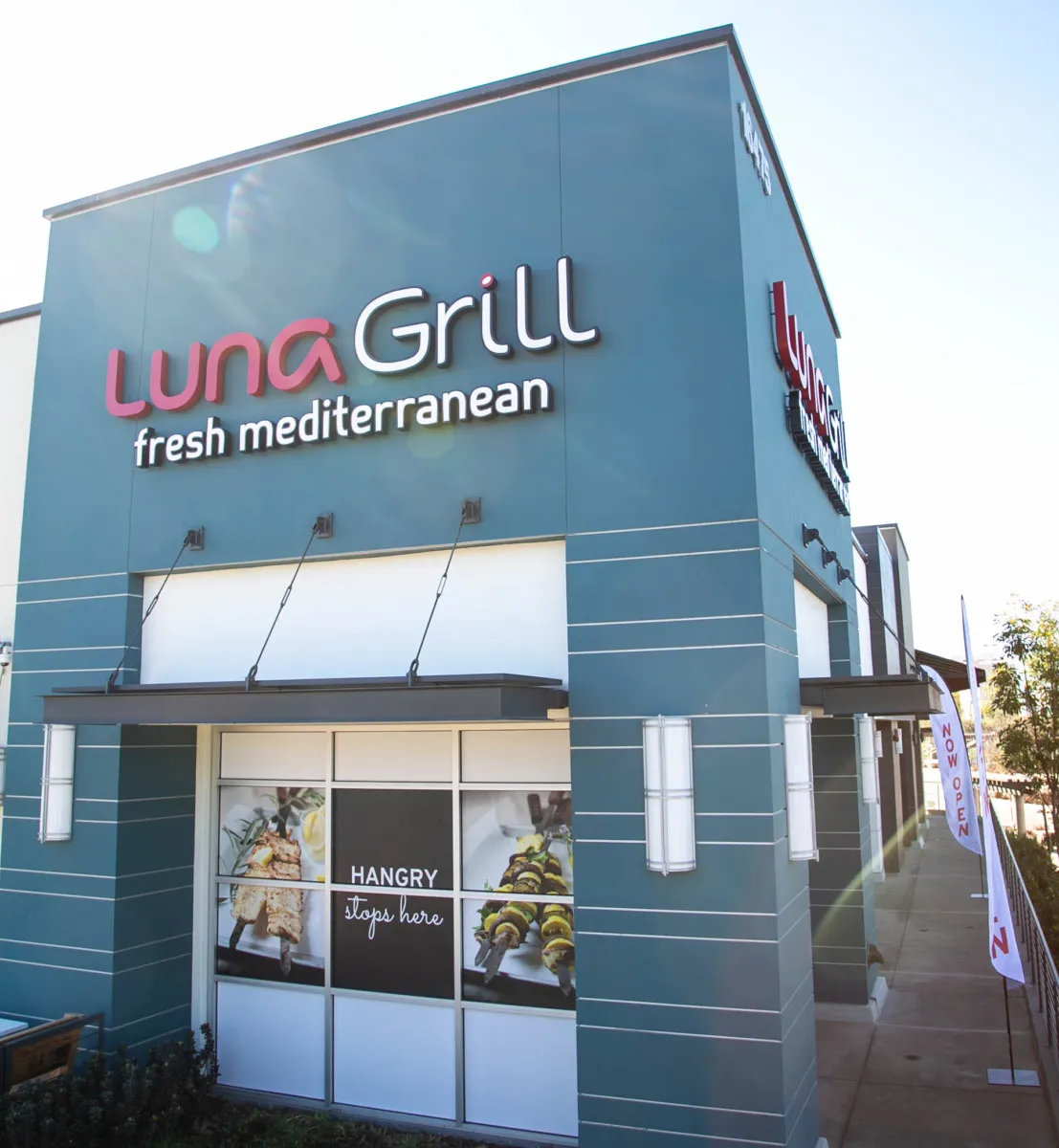 A freestanding teal restaurant exterior with the lockup on the parapet