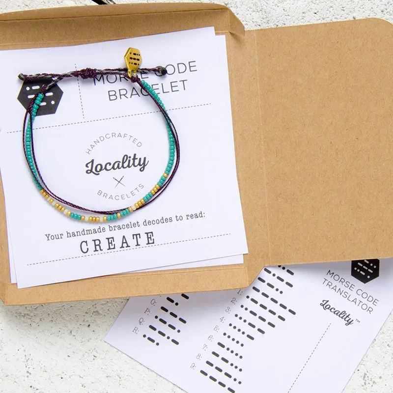 A hand-stamped kraft Locality box being opened to reveal a bracelet inside.